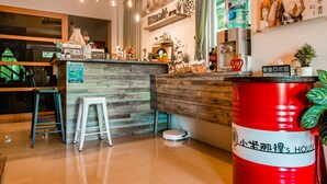 Un interior moderno con mostrador de madera, taburetes, un barril rojo y varios objetos decorativos.