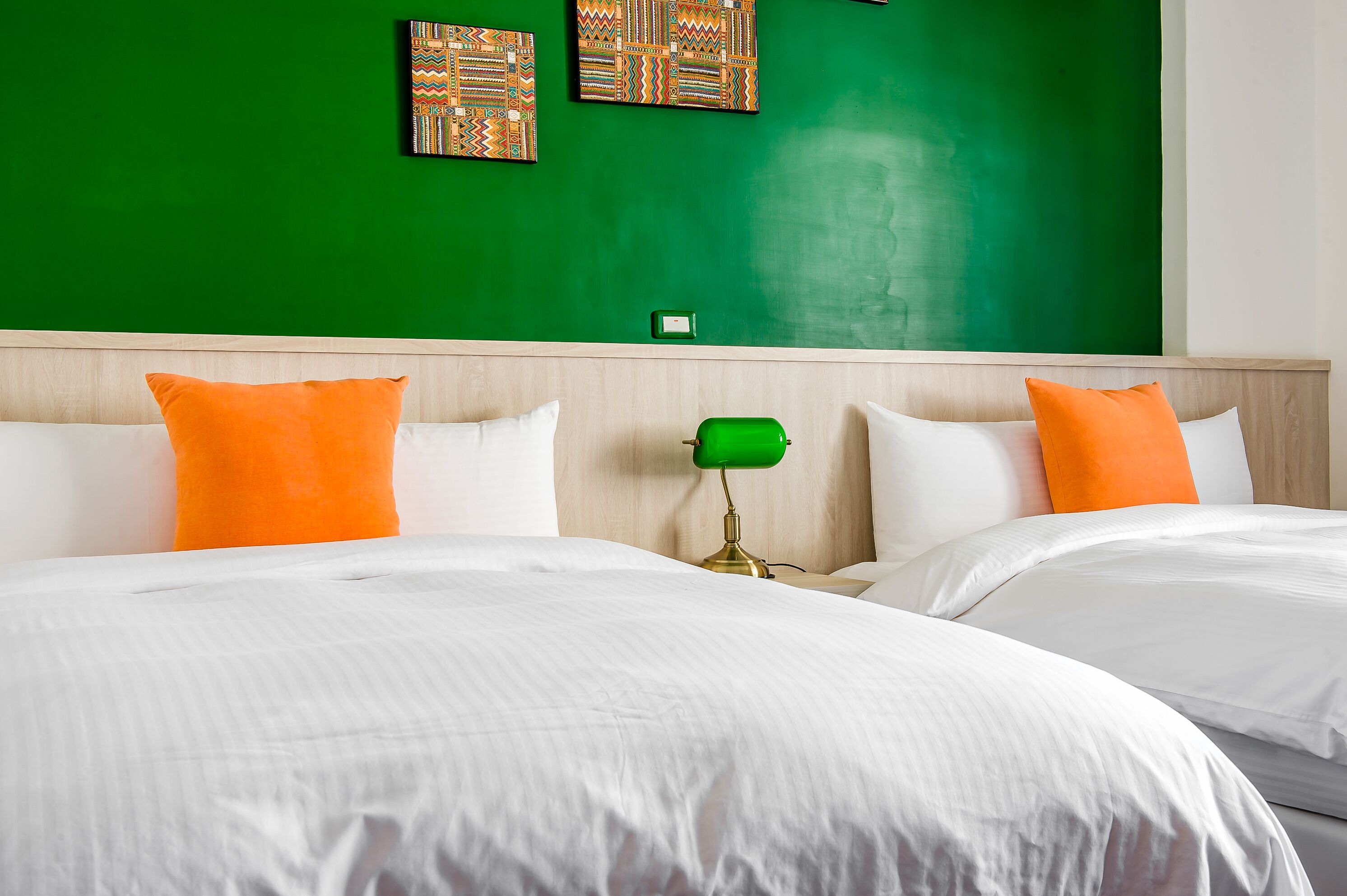 A hotel room with two beds, white bedding, and orange pillows.