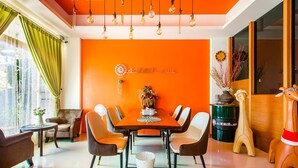 Un comedor moderno con una pared de color naranja brillante, una mesa de madera y sillas contemporáneas.