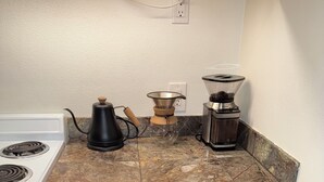 Et køkken med komfur, kaffemaskine og kværn.