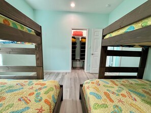 Ein Zimmer mit Stockbetten, einem Schrank und einer Tür zu einem weiteren Raum.
