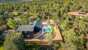 Un quartier résidentiel avec une maison dotée d’une piscine, entourée d’arbres et avec des montagnes en arrière-plan.