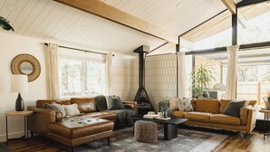 Una sala acogedora con chimenea, dos sofás, una mesa de centro y un ventanal grande.