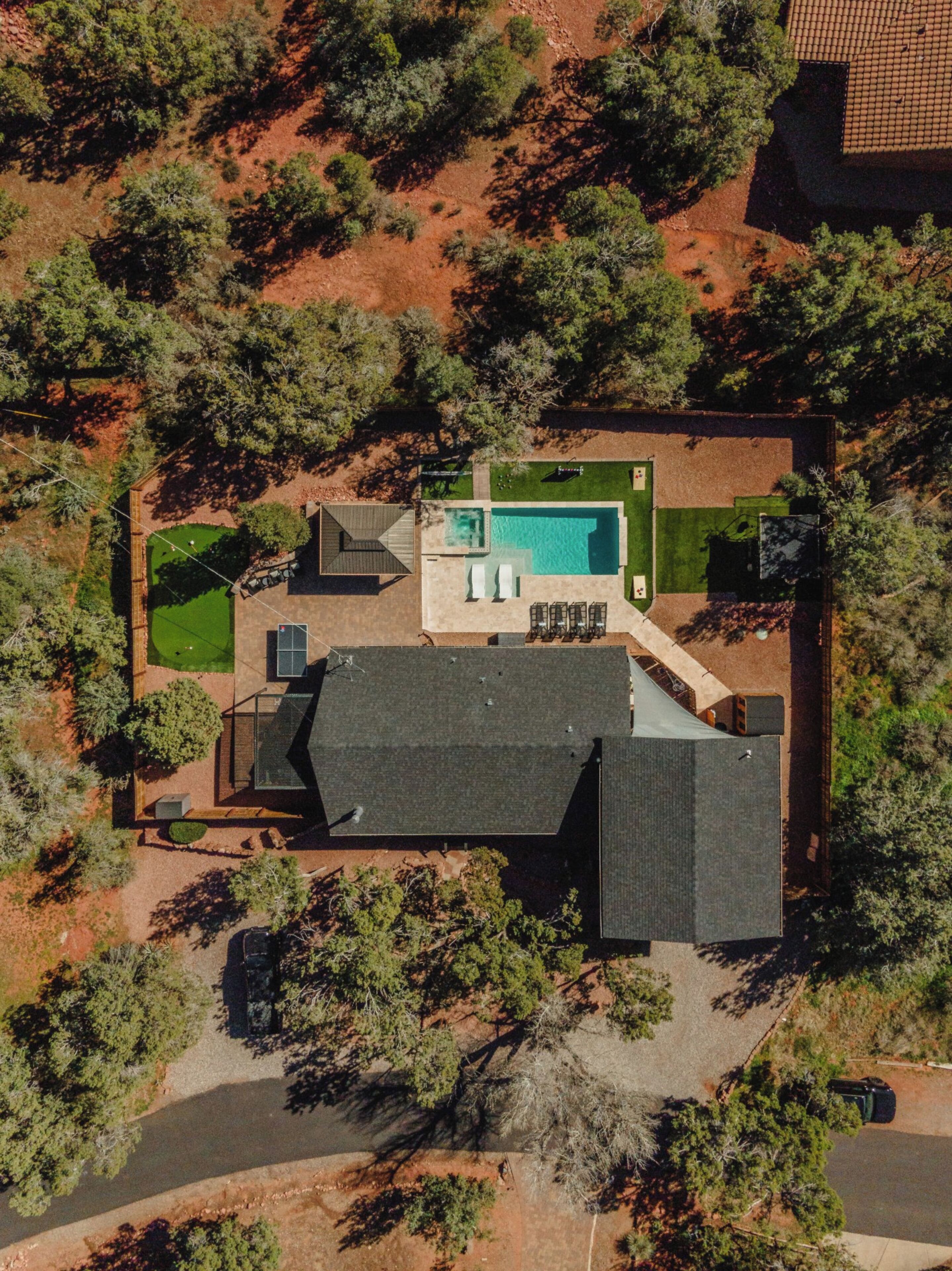 An aerial view of a residential property with a swimming pool, a covered patio, and a fenced yard.