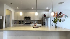 A modern kitchen with white cabinets, stainless steel appliances, and pendant lighting. - Luxury 13 Bedroom Villa in Orlando , Orlando Villa 6269 (Orlando)