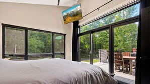 Un dormitorio con una cama grande, varias ventanas y un televisor montado en la pared.