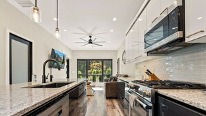 Una cocina moderna con encimeras de granito, electrodomésticos de acero inoxidable y un amplio ventanal con vistas al exterior.