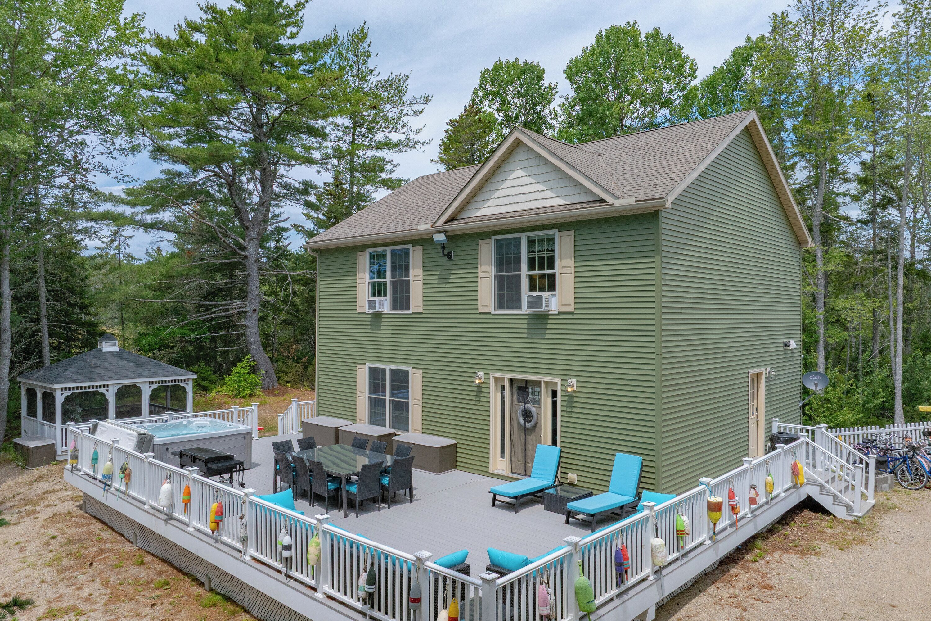 A two-story house with a covered patio area featuring outdoor furniture.