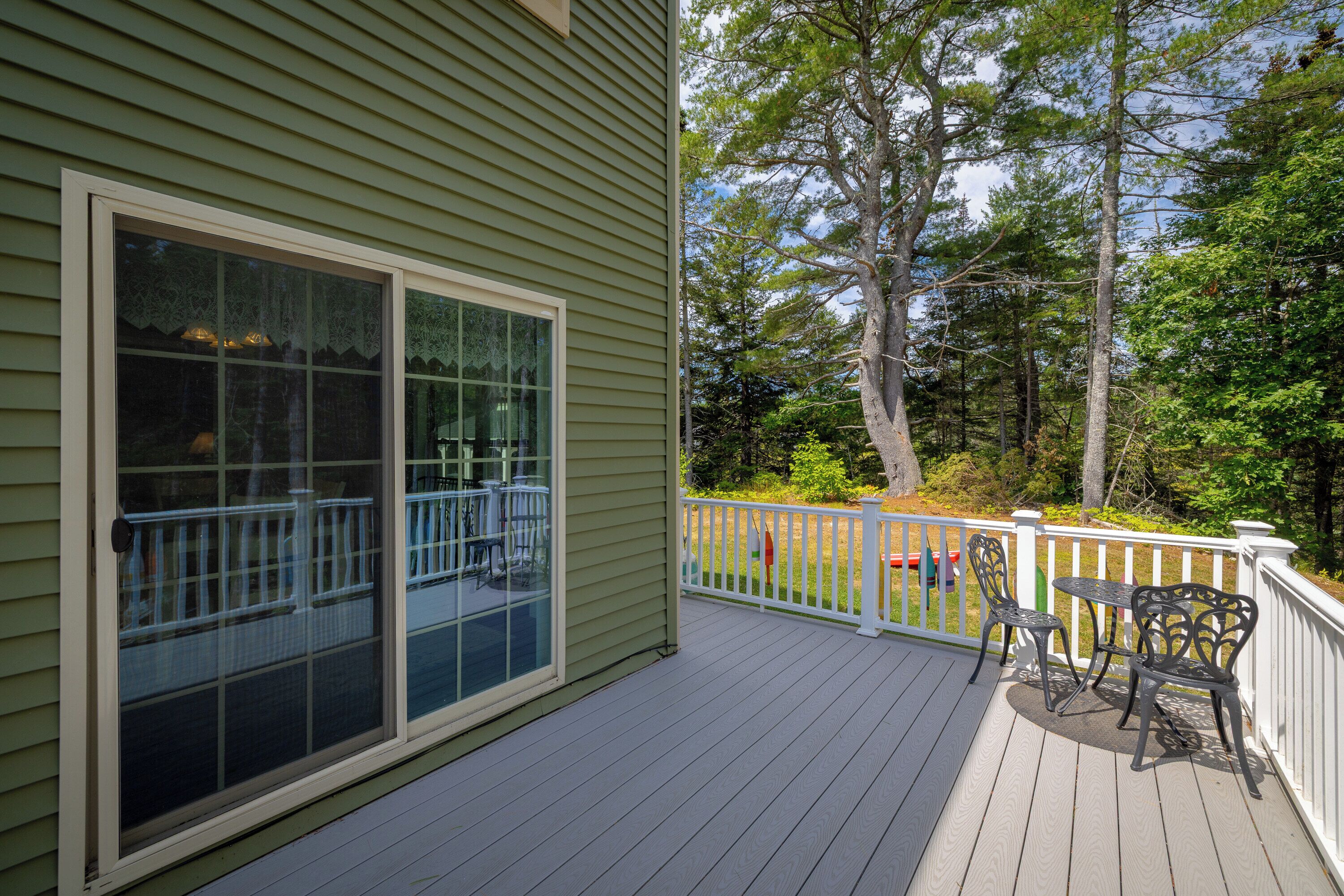 A wooden deck with a white railing, a table, and two chairs.