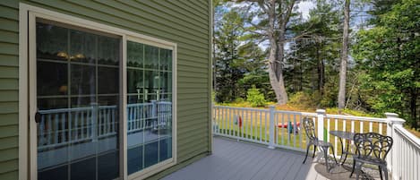 A wooden deck with a white railing, a table, and two chairs.