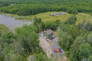 A lodge with a large deck, a swimming pool, and a boat.