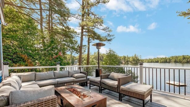 Une terrasse dotée de mobilier d’extérieur, d’un foyer et offrant une vue sur un lac.