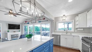 Une cuisine moderne avec des armoires blanches, un grand îlot central et une cuisinière intégrée.