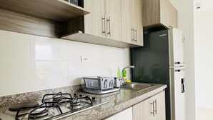 Una cuina moderna amb armaris de fusta, forns de gas, microones i nevera.