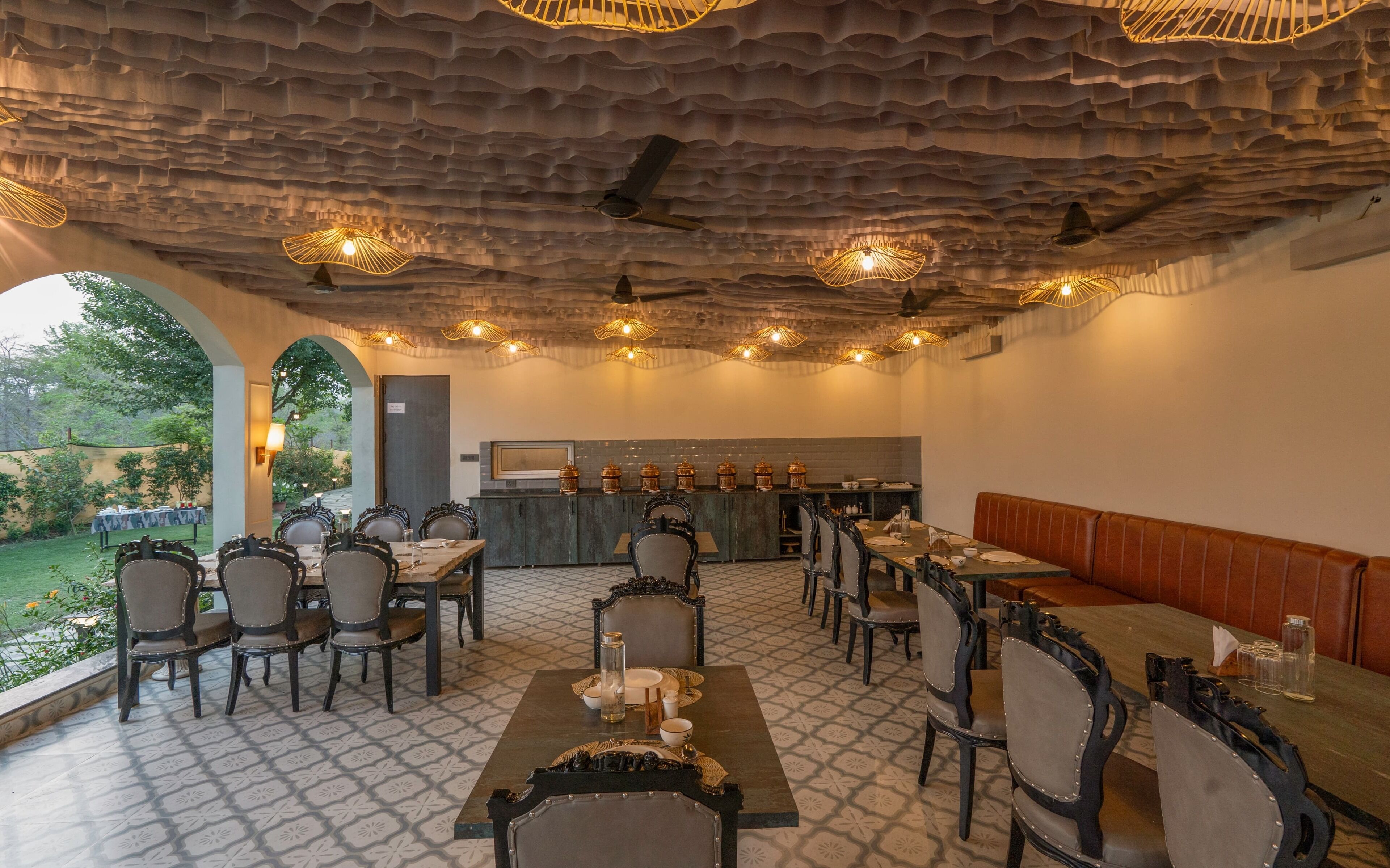 A restaurant with a rustic ceiling, multiple tables and chairs, and a bar area.