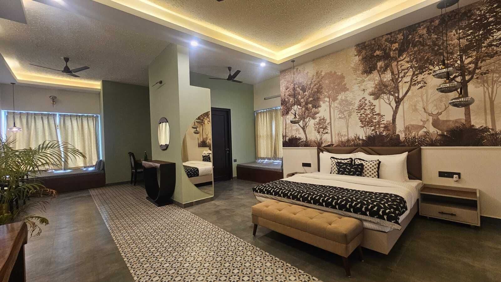 Une chambre moderne avec un grand lit, un coin salon comprenant un fauteuil, une petite table et un grand miroir.