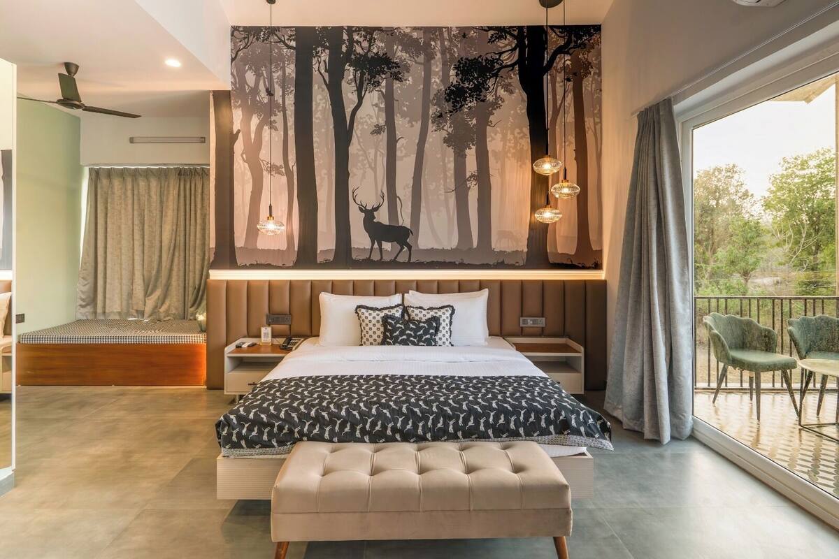 A modern bedroom with a large bed, a bench, a nightstand, and a view of the outdoors.