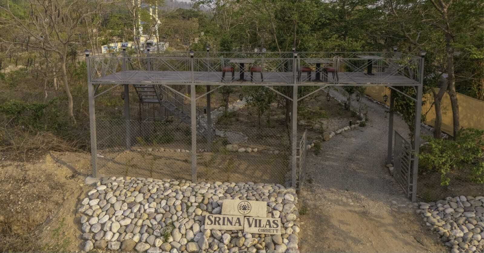 A metal structure with a sign reading "SRINA VILAS CORBETT" in front of a rocky path.
