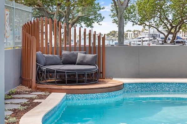 Relax by the pool surrounded by lush greenery and a marina view.