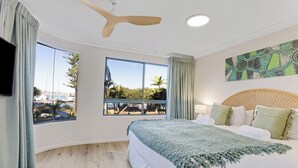 A bedroom with a large bed, a ceiling fan, and a view of a marina through large windows. - Riverdance Apt 6  (Mooloolaba)