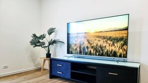 Un soggiorno moderno con una televisione a schermo piatto su un mobile nero, un tavolino in legno e una pianta in vaso.