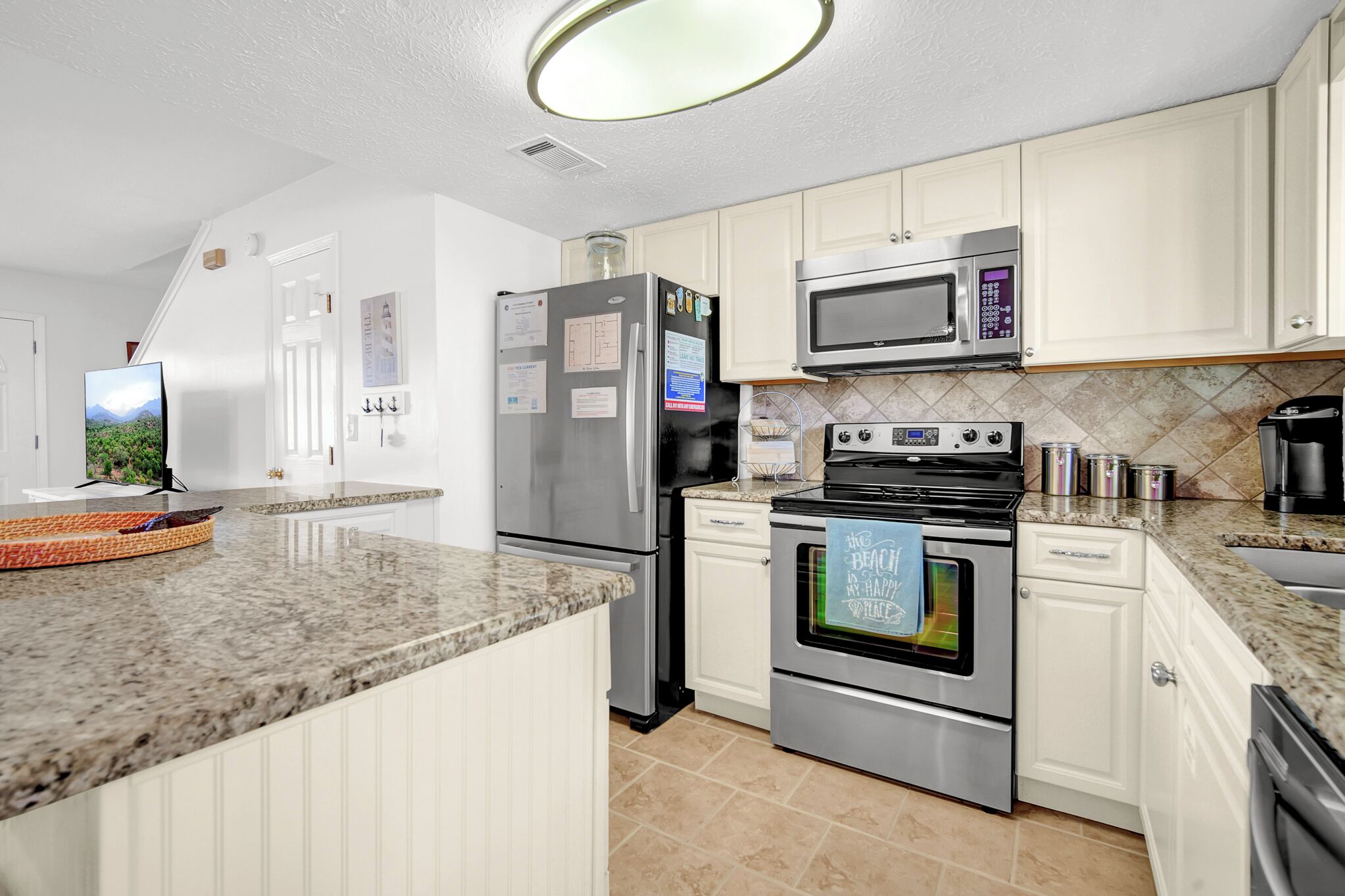 A modern kitchen with white cabinets, stainless steel appliances, and a granite countertop.