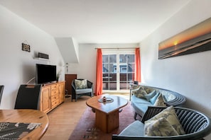 Una sala de estar con televisor, aparador de madera, sofá y mesa de comedor.
