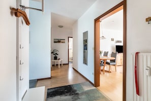 Un pasillo que conduce a un comedor con una mesa y sillas, una planta en maceta y un radiador.