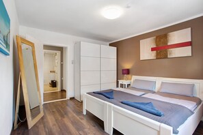 Un dormitorio con cama, armario, espejo y un cuadro en la pared.