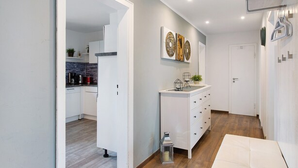 A modern kitchen with white cabinets, a black countertop, and a brick backsplash. - Coastal Love Apartment – Close to Park & City (Wilhelmshaven)