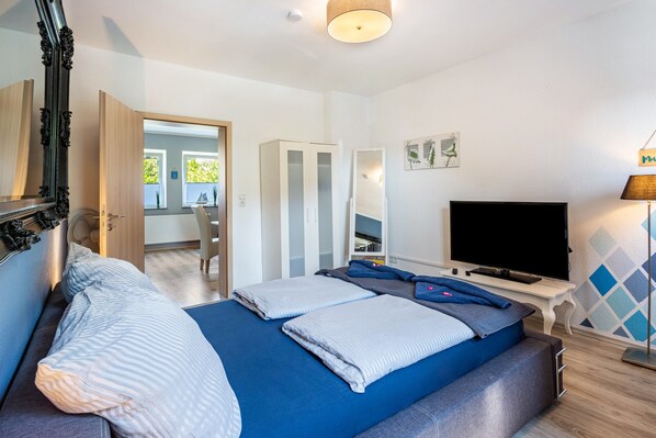 Une chambre à coucher avec un lit, une télévision, un miroir et une armoire.