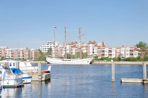 A marina with a large sailing ship docked, surrounded by residential buildings.