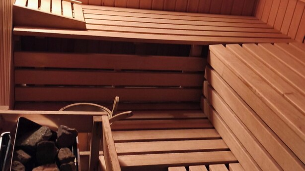 Un sauna avec des bancs en bois et un banc doté d’une structure métallique.