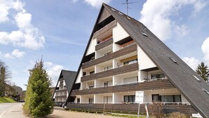 Un immeuble à plusieurs étages, doté de balcons, d’un toit en pente et d’une enseigne indiquant un prix de 17.
