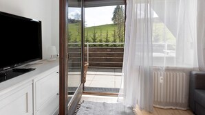 Une chambre équipée d’une télévision, d’une lampe, d’une porte-fenêtre coulissante donnant sur un balcon et d’un radiateur.