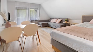 Une chambre à coucher moderne comprenant un lit, un canapé, une table à manger avec des chaises et une petite table d’appoint.