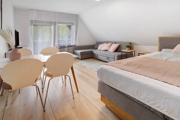 Une chambre à coucher moderne comprenant un lit, un canapé, une table à manger avec des chaises et une petite table d’appoint.