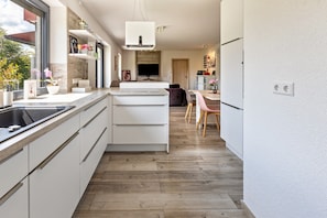 A modern kitchen with white cabinetry, a built-in oven, and a large window.