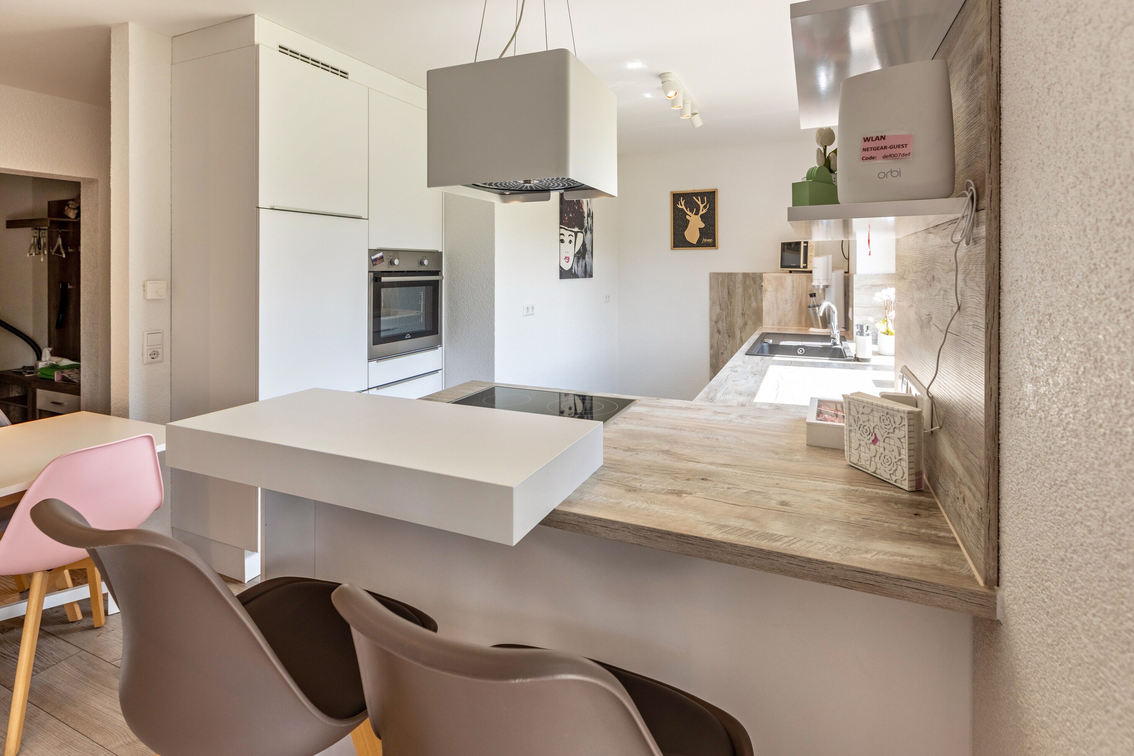 Eine moderne Küche mit Kochinsel, Essbereich mit Stühlen und einem sichtbaren Backofen.