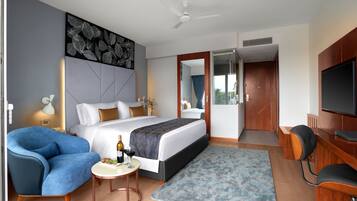 Habitación de hotel moderna con una cama grande, un escritorio, una silla, un televisor y un ventilador de techo.