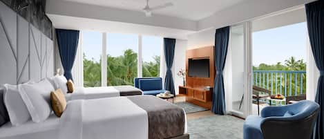A modern hotel room with a large bed, a desk, a chair, a TV, and a balcony with a view of palm trees.