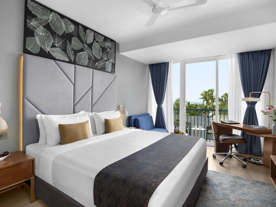 Una habitación de hotel moderna con una cama grande, un escritorio y un balcón con vistas.