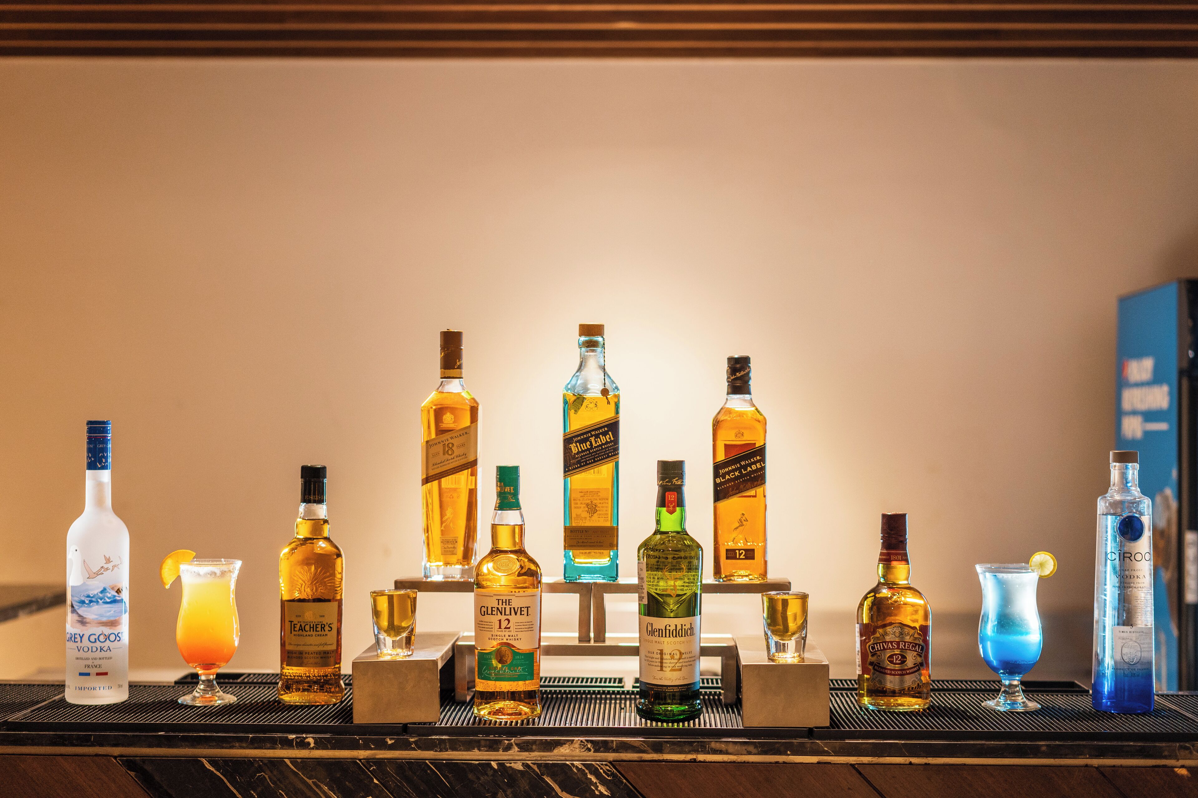 A bar area with various bottles of liquor and glasses of drinks.