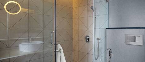 A modern bathroom with a glass-enclosed shower, a white sink, and a towel rack.
