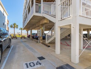 A parking area with a concrete floor, marked parking space 104, and a staircase leading to a building with balconies.