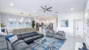 A modern living room with a grey sectional sofa, a glass coffee table, and a blue rug.