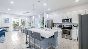 A modern kitchen with white cabinets, stainless steel appliances, and a central island with bar stools.