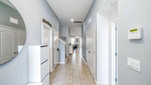 A hallway with white doors, a kitchen area, and a bathroom.