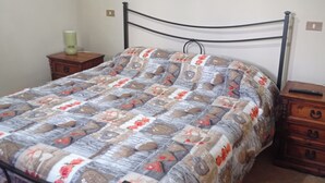 Un lit avec une couette, une table de chevet, une lampe et une commode.