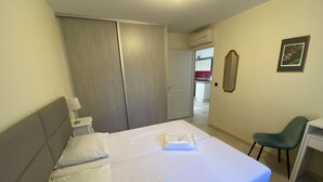 Ett hotellrum med en säng, ett skrivbord, en stol, en garderob och en spegel.